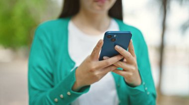 Parkta akıllı telefon kullanan Çinli genç bir kadın.