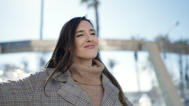 Güzel İspanyol kadın gülümsüyor. Parkta kolları açık duruyor.