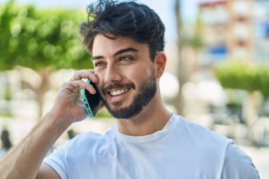 Genç İspanyol adam gülümsüyor. Kendine güveniyor. Sokakta akıllı telefondan konuşuyor.