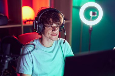 Oyun odasında bilgisayar kullanarak video oyunu oynayan genç sarışın adam.