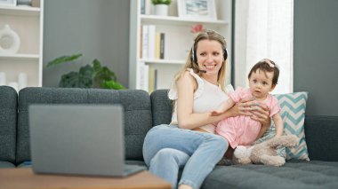 Anne ve kızı evde bebek bakıcılığı yaparken çalışıyor.