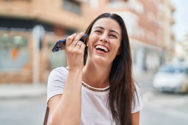 Genç ve güzel İspanyol kadın gülümsüyor. Caddedeki akıllı telefondan kendine güvenen bir sesli mesaj dinliyor.