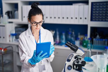 Young caucasian woman scientist using touchpad with relaxed expression at laboratory