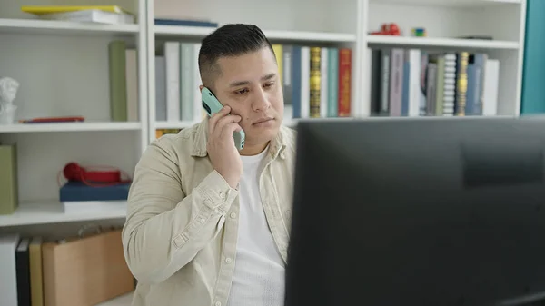 Young Hispanic Man Student Using Computer Talking Smartphone Library University — Stockfoto
