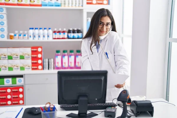 Молодая Латиноамериканка Фармацевтка Разговаривает Телефону Читающим Документом Аптеке — стоковое фото