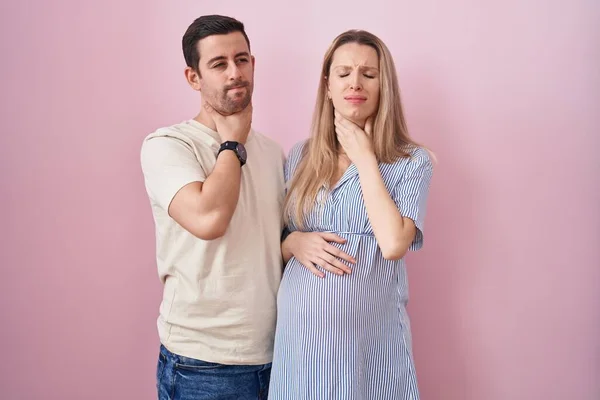 Casal Jovem Esperando Bebê Sobre Fundo Rosa Tocando Pescoço Doloroso — Fotografia de Stock