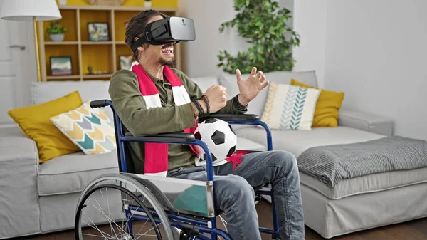 年轻的他的惊慌失措的男人坐在轮椅上 用虚拟现实眼镜观看足球比赛 — 图库照片