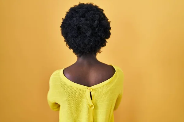 站在黄色工作室上方的非洲年轻女子向后站着 交叉着双臂望着别处 — 图库照片