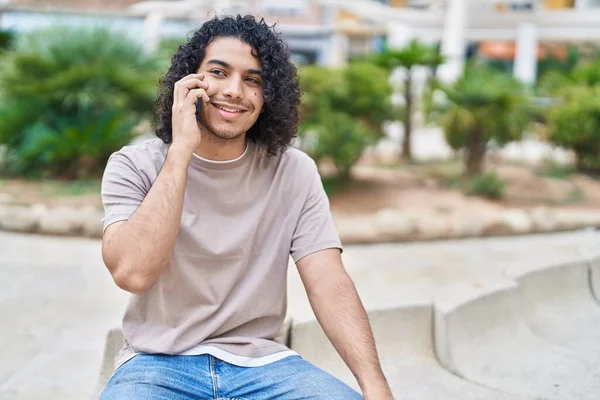 Νεαρός Λατίνος Μιλάει Στο Smartphone Κάθεται Στον Πάγκο Στο Πάρκο — Φωτογραφία Αρχείου