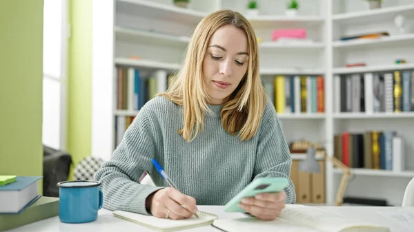 Junge Blonde Studentin Schreibt Mit Smartphone Notizen Bibliothek — Stockfoto