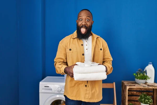 Afričan Američan Drží Čisté Ručníky Prádelně Vyčnívat Jazyk Šťastný Legračním — Stock fotografie
