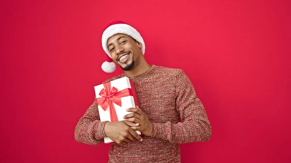 Hombre Afroamericano Sosteniendo Regalo Navidad Sobre Fondo Rojo Aislado — Foto de Stock