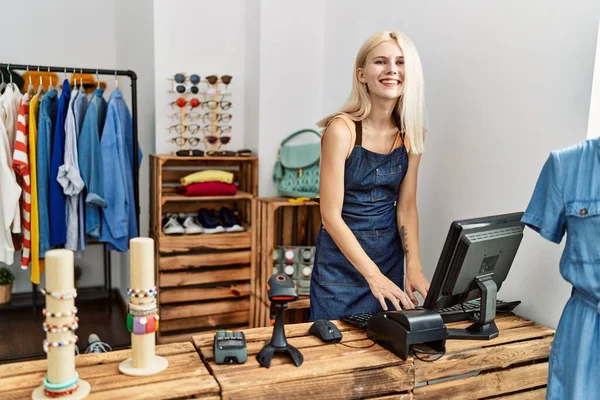 在服装店使用电脑时 年轻的金发女售货员带着自信的微笑 — 图库照片