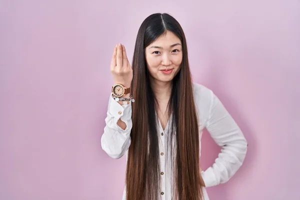中国の若いです女性立ち上のピンクの背景行いますイタリアのジェスチャーとともに手と指確信式 — ストック写真