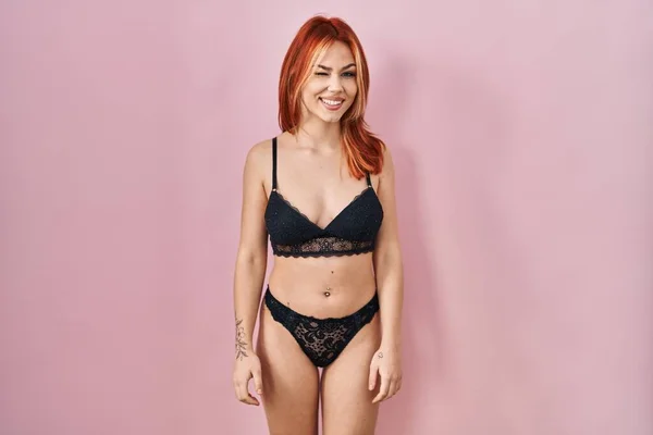 Young Caucasian Woman Wearing Lingerie Pink Background Winking Looking Camera — Stockfoto