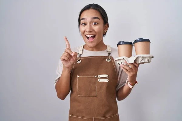 Młoda Latynoska Kobieta Nosząca Profesjonalny Fartuch Kelnerski Trzymająca Kawę Wskazującą — Zdjęcie stockowe