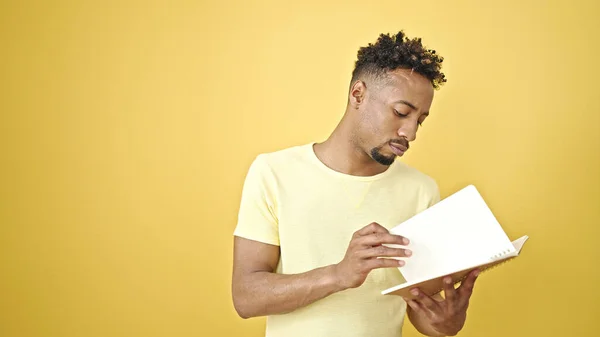 アフリカ系アメリカ人男性読書本上の隔離された黄色の背景 — ストック写真