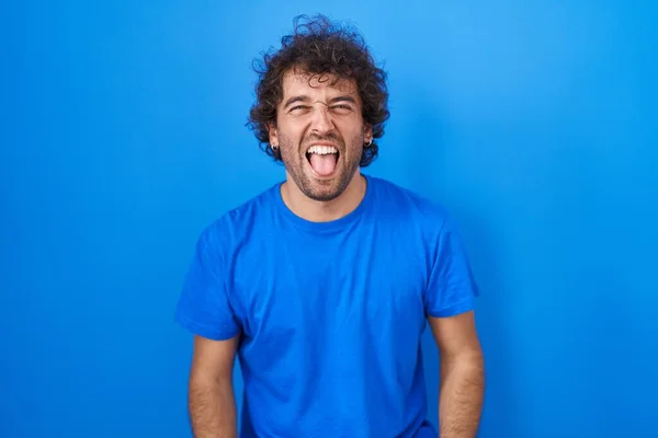 Іспанський Молодий Чоловік Стоїть Над Синім Фоном Радіючи Смішним Виразом — стокове фото
