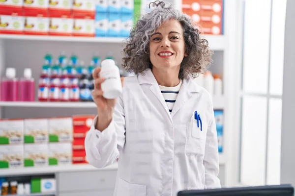 Średniowłosy Kobieta Farmaceuta Uśmiechnięta Pewnie Trzymając Butelkę Tabletek Aptece — Zdjęcie stockowe