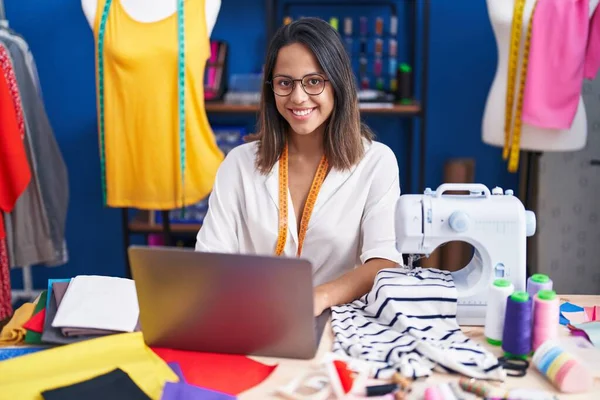 Young Hispanic Woman Tailor Smiling Confident Using Laptop Sewing Studio — Foto Stock