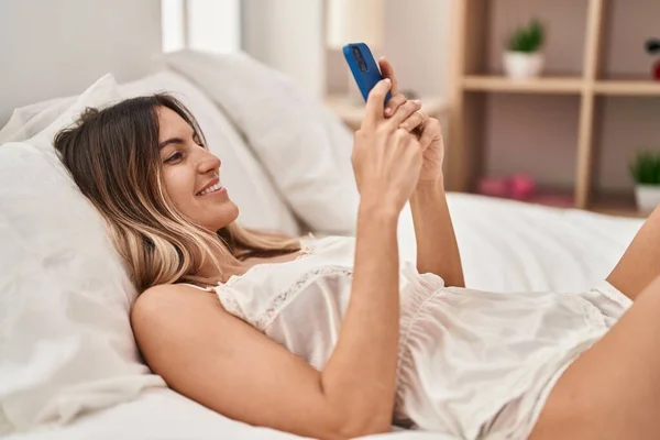 寝室のベッドに横たわっスマートフォンを使用して若い女性 — ストック写真