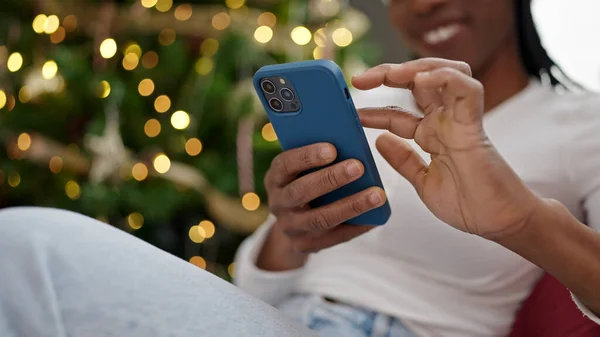Afroamerykanka Pomocą Smartfona Siedzi Przy Choince Domu — Zdjęcie stockowe