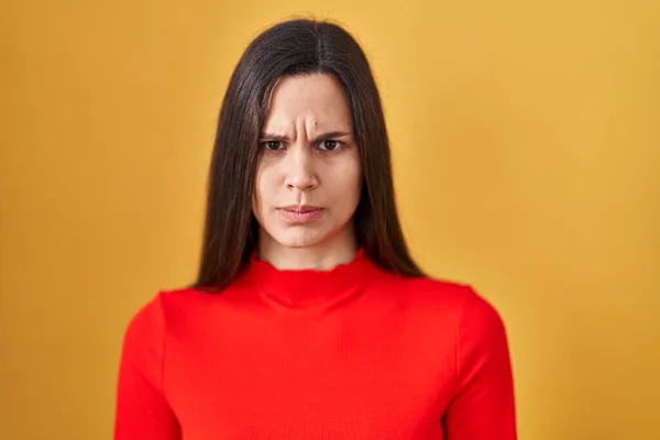 若いヒスパニック系の女性は黄色の背景懐疑的で神経の上に立って 問題のために動揺を眉をひそめて 否定的な人 — ストック写真
