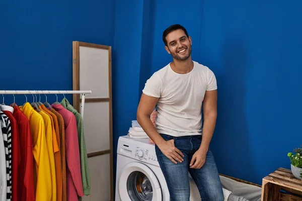 年轻的惊慌失措的男人自信地坐在洗衣房的洗衣机上 — 图库照片