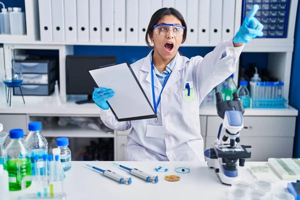 Латиноамериканская Молодая Женщина Работающая Лаборатории Учёных Удивлённым Впереди Пальцем Открытым — стоковое фото