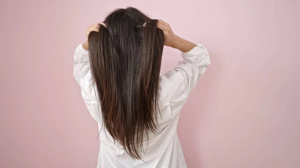 Молода Красива Іспаномовна Жінка Розчісує Волосся Руками Над Ізольованим Рожевим — стокове фото