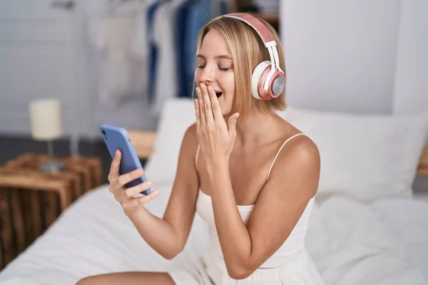 Genç Sarışın Kadın Yatak Odasında Esneyerek Müzik Dinliyor — Stok fotoğraf