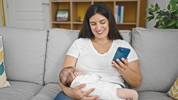 Anne Kız Bebek Kanepede Oturmuş Bebeği Kucağında Tutuyorlar Akıllı Telefon — Stok fotoğraf