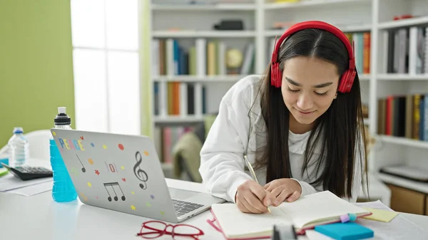 Junge Schöne Hispanische Studentin Schreibt Mit Laptop Und Kopfhörer Notizen — Stockfoto