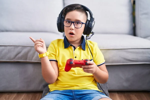 Joven Niño Hispano Jugando Videojuego Sosteniendo Controlador Usando Auriculares Sorprendidos —  Fotos de Stock