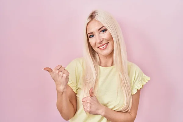 Caucasian Woman Standing Pink Background Pointing Back Hand Thumbs Smiling — Stock Photo, Image