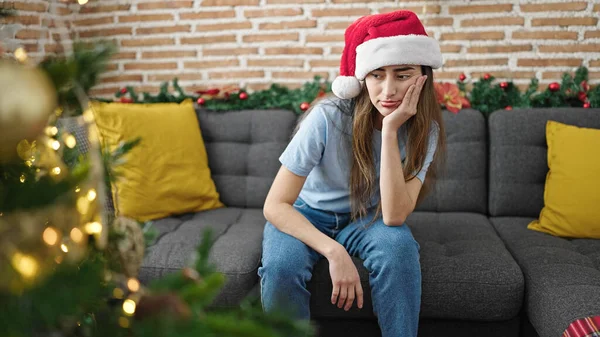 年轻美丽的惊慌失措的女人坐在沙发上庆祝圣诞节 看起来很不开心 — 图库照片