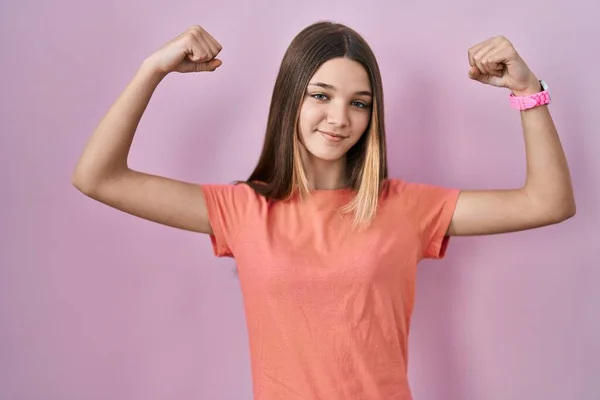 站在粉色背景上的少女露出胳膊肌肉微笑 感到自豪 健身概念 — 图库照片