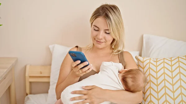 Mother Daughter Sitting Bed Breastfeeding Baby Using Smartphone Bedroom — Stock Photo, Image