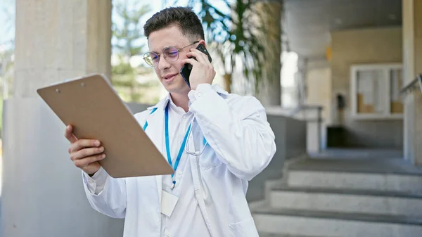 Joven Médico Hispano Hablando Documento Lectura Teléfonos Inteligentes Hospital —  Fotos de Stock
