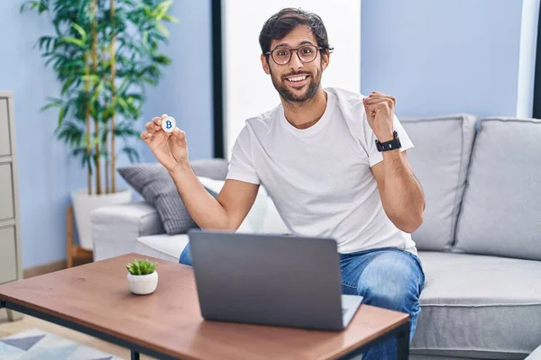 Handsome Latin Man Holding Virtual Currency Bitcoin Using Laptop Screaming — Stock Photo, Image