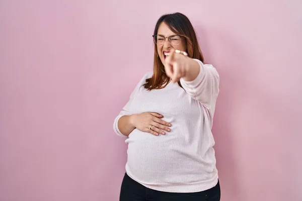 Těhotná Žena Stojí Nad Růžovým Pozadím Směje Vám Ukazuje Prstem — Stock fotografie