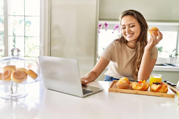 年轻美丽的惊慌失措的女人在厨房用笔记本电脑吃早餐 — 图库照片