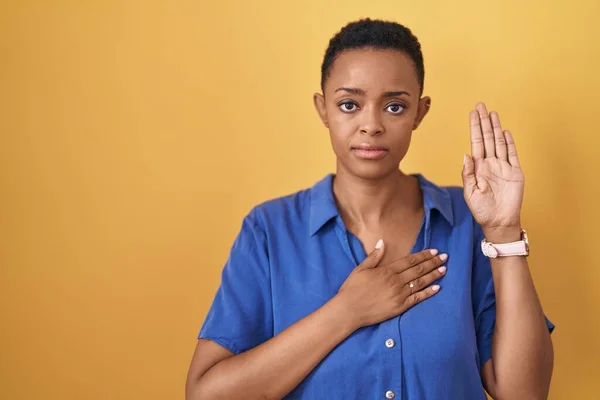 胸と手の平に手をつけて黄色の背景を身に着けているアフリカ系アメリカ人女性忠誠を誓う — ストック写真