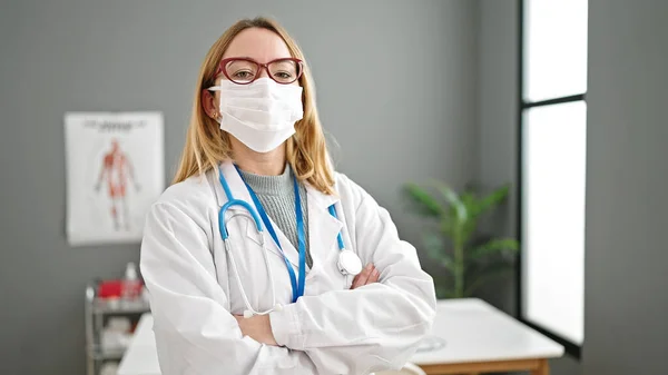 Sarışın Kadın Doktor Klinikte Kollarını Kavuşturup Tıbbi Maske Takıyor — Stok fotoğraf