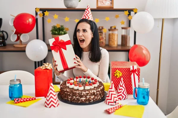 Mujer Hispana Celebrando Cumpleaños Con Pastel Sosteniendo Presente Enojado Loco — Foto de Stock