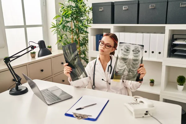 年轻的高加索女医生坐在诊所的桌子上 看起来像X光片 — 图库照片