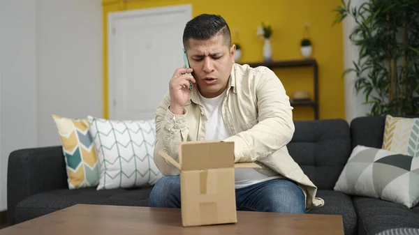Młody Hiszpan Rozmawia Przez Telefon Rozpakowując Kartonowe Pudełko Domu — Zdjęcie stockowe