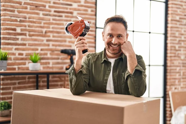 stock image Young caucasian man smiling confident packing cardboard box at new home