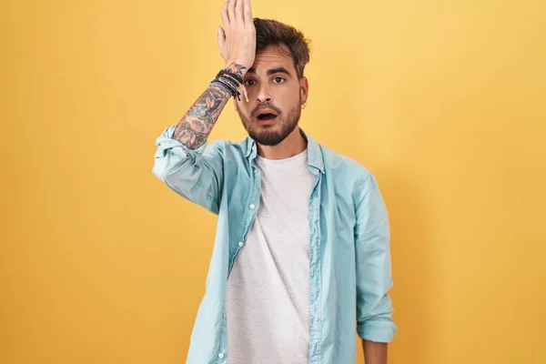 Jovem Hispânico Com Tatuagens Sobre Fundo Amarelo Surpreso Com Mão — Fotografia de Stock