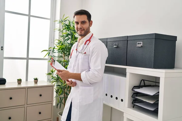 Young Hispanic Man Wearing Doctor Uniform Holding Clipboard Clinic — Stock Photo, Image